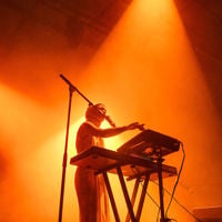A musician performing is bathed in an orange glow on stage at Illuminate Adelaide 