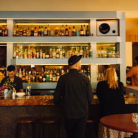 Two people stand in front of the bar stacked with liquor at Latteria on Hutt Street 