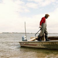 A man standing on a small tin boat in the coorong waters