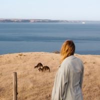 A young woman looking at a kangaroo on a hill