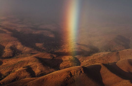 a rainbow beam shining down between the dark ranges