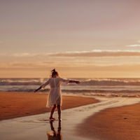 a young girl playing in the sand at sunset