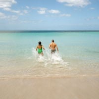 two people running into the ocean