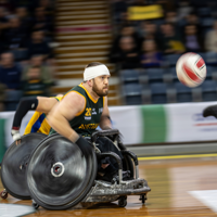 A man in a wheelchair races toward the ball at a Wheelchair Rugby event 
